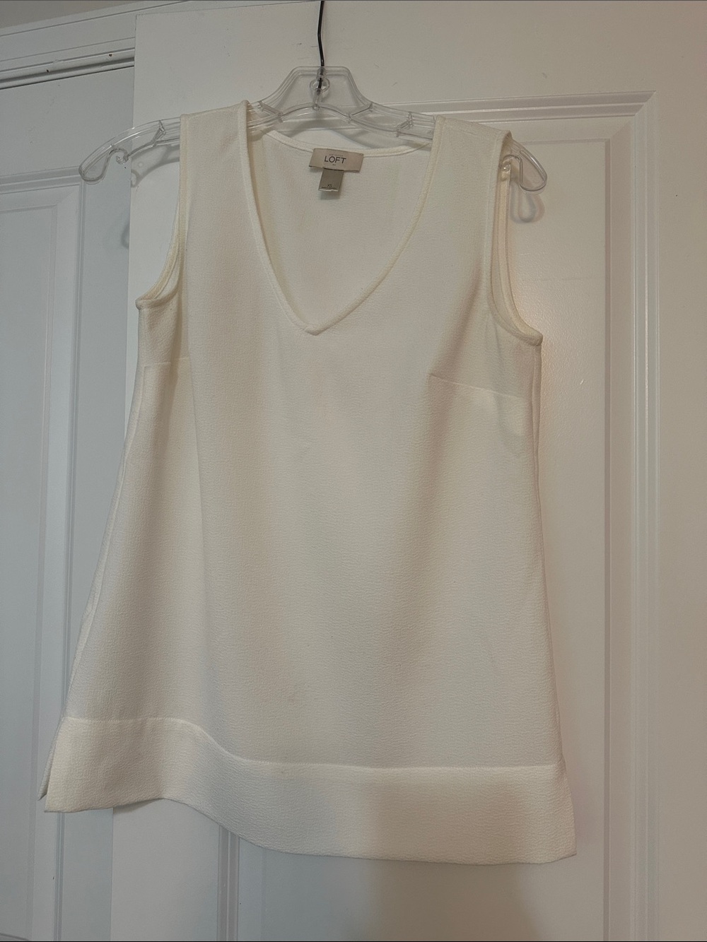 Sz XS Loft Ivory sleeveless top features a v-neckline and a layered hem detail.